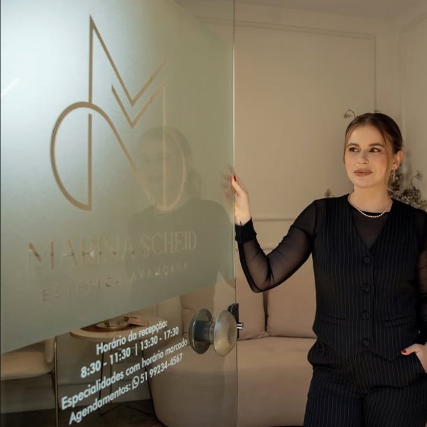 Dra. Marina Scheid na entrada de vidro da clínica Marina Scheid Estética Avançada