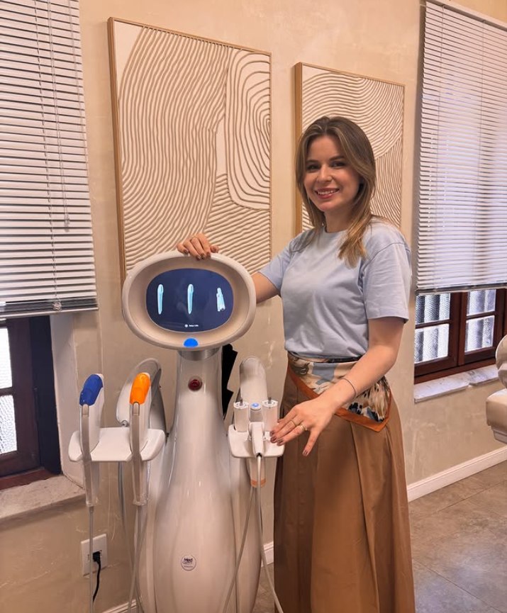Dra. Marina Scheid ao lado do equipamento de tratamento de flacidez na clínica